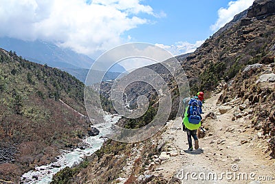 Nepalese sherpa porters walks on footpath carrying heavy load Stock Photo