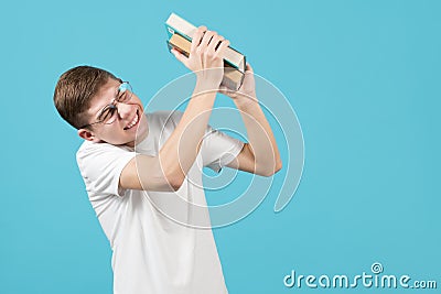 The nerd squints and as if trying to protect himself, keeps books aside Stock Photo