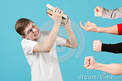 The nerd is trying to brush off books from bullies who want to offend him Stock Photo