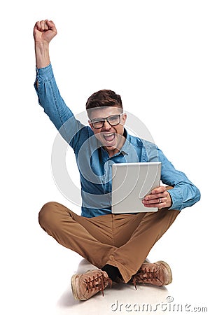 Nerdy student celebrates very good news he reads on tablet Stock Photo