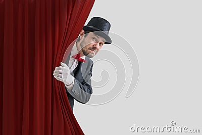 Nervous actor or illusionist is hiding behind red curtain in theater Stock Photo