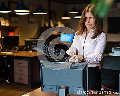 Nervous breakdown at work. Business woman freaks out and breaks the computer in the office Stock Photo