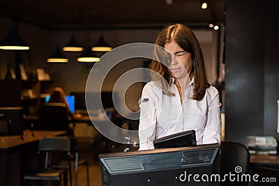 Nervous breakdown at work. Business woman freaks out and breaks the computer in the office Stock Photo