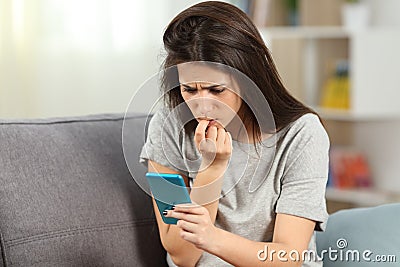 Nervous girl biting nails reading phone content Stock Photo