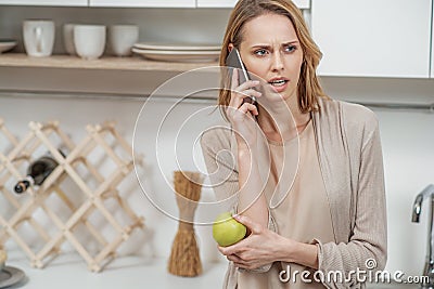 Nervous lady talking on phone in cook room Stock Photo