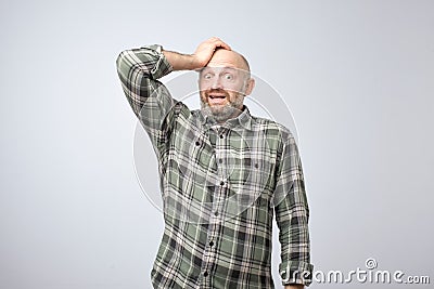 Nervous scared european guy has sorrorful expression, holding hands on head finds out about tragic event. Stock Photo