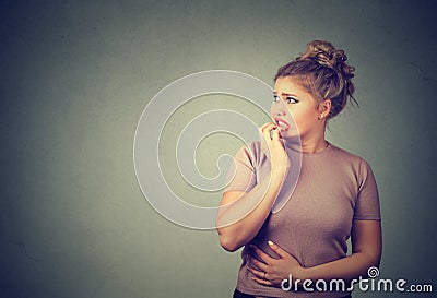 Nervous stressed young concerned woman biting fingernails looking anxiously Stock Photo