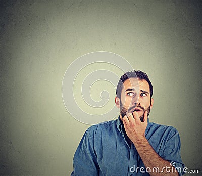 Nervous stressed young man student biting fingernails looking up Stock Photo