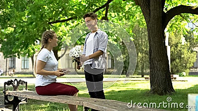 Nervous teenager presenting flowers to pretty girl in park, pick up master Stock Photo