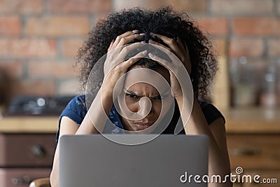 Nervous young african female scratch head stare at laptop screen Stock Photo