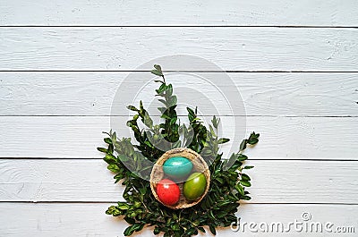 Nest colored eggs wreath on white wooden planks background Stock Photo