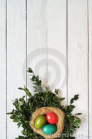 Nest colored eggs wreath on white wooden planks background Stock Photo