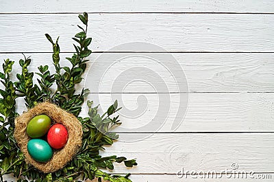 Nest colored eggs wreath on white wooden planks background Stock Photo