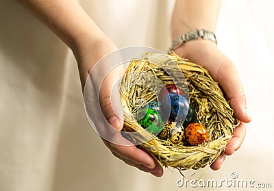 Nest with eggs painted in different colors lie in the palm of the hand Stock Photo