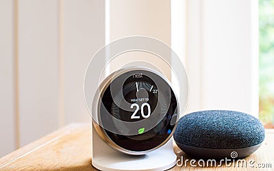 Nest smart thermostat and Google home mini speaker Editorial Stock Photo