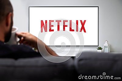 Netflix on smart TV. Man with a mug and watching Netflix Logo on the screen. ROSARIO, ARGENTINA - MARCH 28, 2023 Editorial Stock Photo