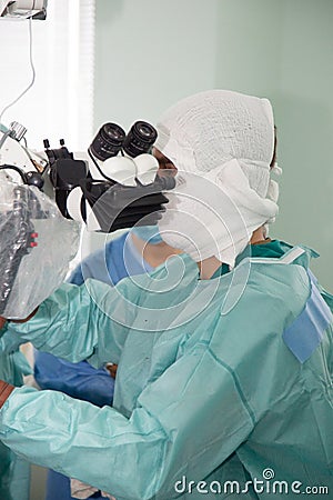 A neurosurgeon doctor looks into a microscope during an operation. Neurosurgery and microsurgery. Stock Photo