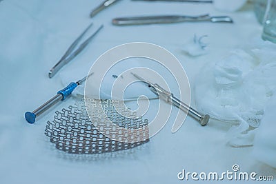 Neurosurgical instruments, including a titanium plate for implantation in the skull, are on the sterile operating table of a nurse Stock Photo