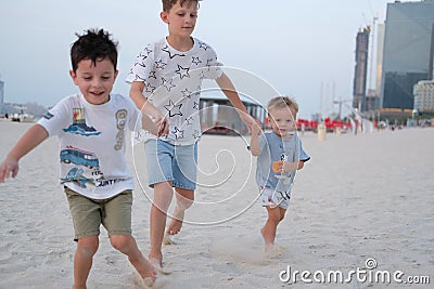 Three brothers are running on the beach, holding hands Stock Photo