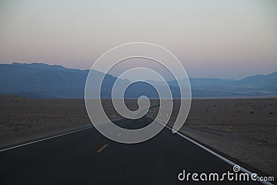 The never ending road during the dusk of a sunset in the Death Valley desert Stock Photo