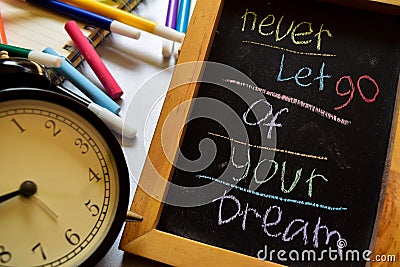 Never let go of your dream on phrase colorful handwritten on chalkboard, alarm clock with motivation and education concepts Stock Photo