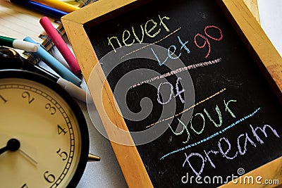 Never let go of your dream on phrase colorful handwritten on chalkboard, alarm clock with motivation and education concepts Stock Photo