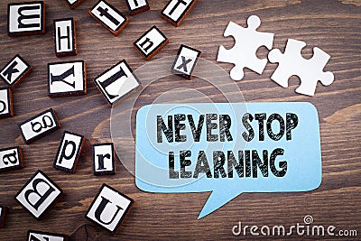 Never stop learning concept. Speech Bubble on a dark textured wooden background Stock Photo