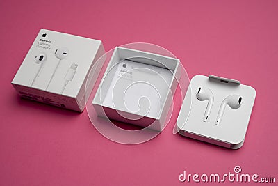 New Apple Earpods, Airpods white earphones for listening to music and podcasts in an open box. Isolated pink background. Budapest Editorial Stock Photo