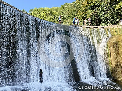 New Athos, Abkhazia, August, 09. 2019. People walking near artificial waterfall on the river Psyrtskha in the summer, the city of Editorial Stock Photo