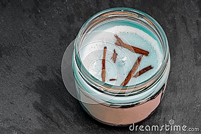 New blue candle with brown twigs and marine scent in a glass jar on a slate plate. Aromatic candle Stock Photo