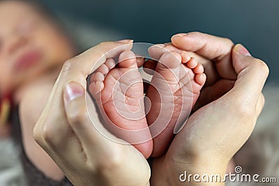 New born baby`s feet in mother hands - hearth shape Stock Photo