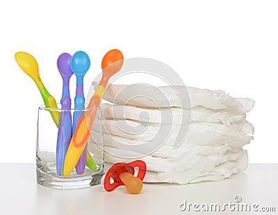 New born child stack of diapers, nipple soother baby feeding spoons Stock Photo