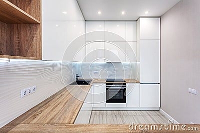 New bright modern kitchen with built in oven and chrome water tap and a wooden table top. Stock Photo