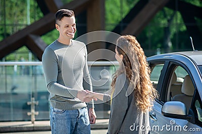 Tall handsome man giving the car keys to the long-haired woman Stock Photo