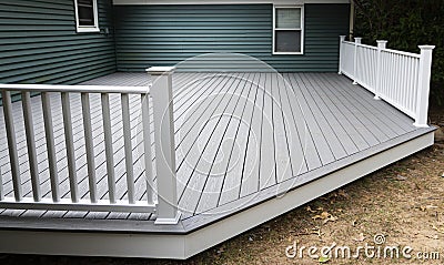 New composite deck on the back of a house with green vinyl siding Stock Photo