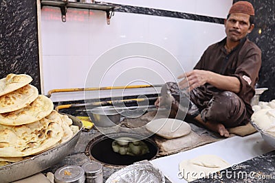 man baking big Tandoori breads in the traditional earth oven during Ramadan. Mughal food Editorial Stock Photo