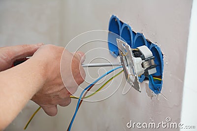 New electrical socket installation. An electrician is attaching a new power outlet with power wires to the electrical box, Stock Photo