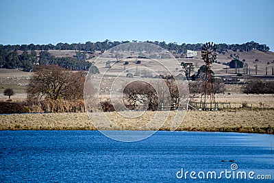 New England farm with windmill and lake Stock Photo
