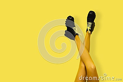 New gray female boots on long slender crossed woman legs in bright yellow tights isolated on yellow background. Pop art concept Stock Photo