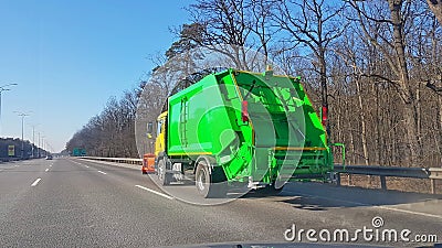 A new green garbage collection vehicle is moving along the highway. Transportation of human waste products. Disposal of municipal Stock Photo
