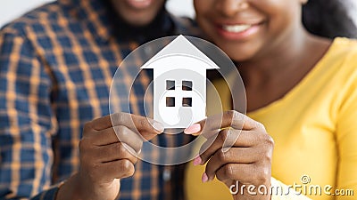 New Home Owners. Happy african american spouses holding paper house figure Stock Photo