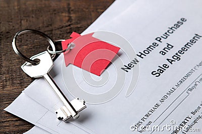 New home purchase and sale agreement. Key with keyring and blank on a brown wooden table. concept of buying a home Stock Photo