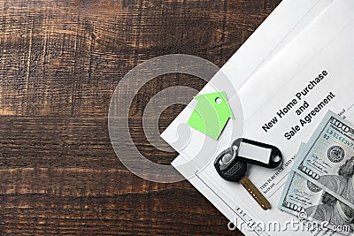 New home purchase and sale agreement. Key with keyring and blank and money on a brown wooden table. concept of buying a home. top Stock Photo