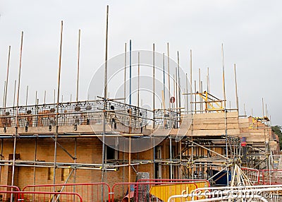 New house with brick wall is being erected and scaffold system placed around it to allow bricklayer to work Stock Photo