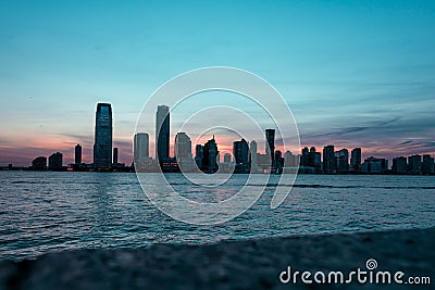 New Jersey cityscape at sunrise with skyscrapers silhouettes and a sea reflecting colors Stock Photo