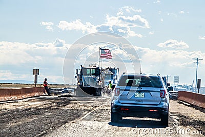 Traffic delay with road construction with workers and trucks with huge American flag and dust and Editorial Stock Photo