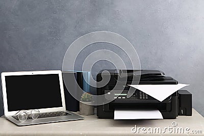 New modern printer and laptop on grey table at workplace Stock Photo