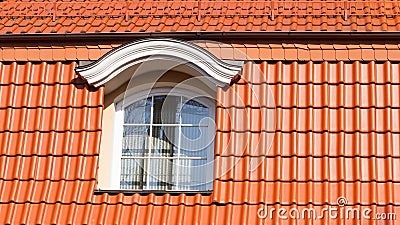 New, modern roof made of red ceramic tiles and a large attic window. Stock Photo