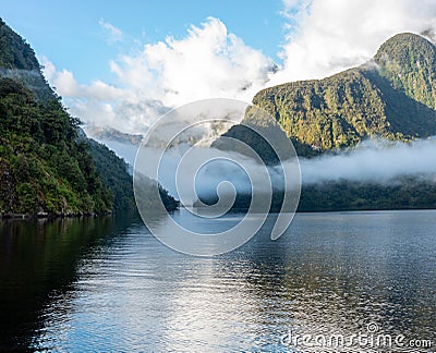 A new morning dawning at Doutful Sound, clouds hanging low in the mountains, Fiordland National Park, New Zealand Stock Photo