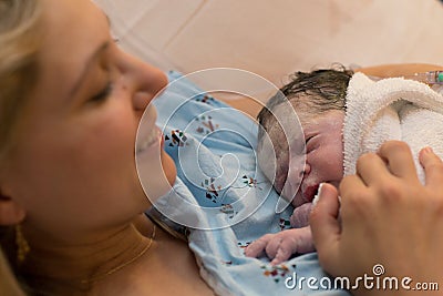 New mother happily holding her newborn child moments after labor Stock Photo